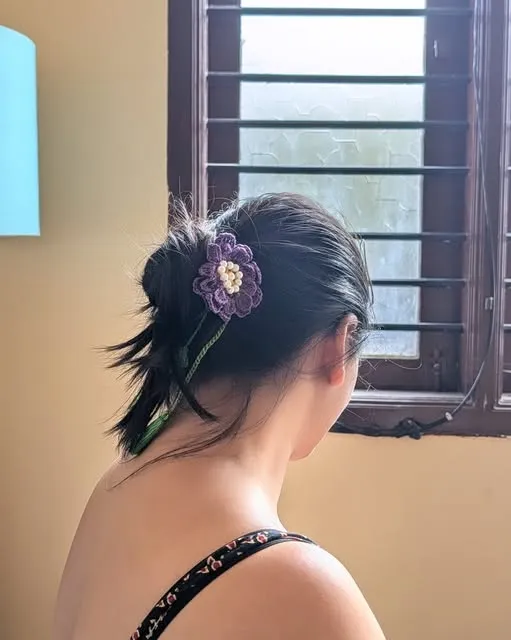 Purple crochet pansy on a claw clip in a low bun