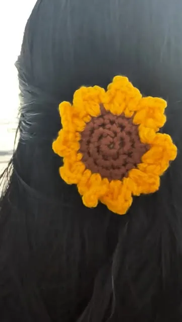 Yellow crochet sunflower hair clip in dark hair