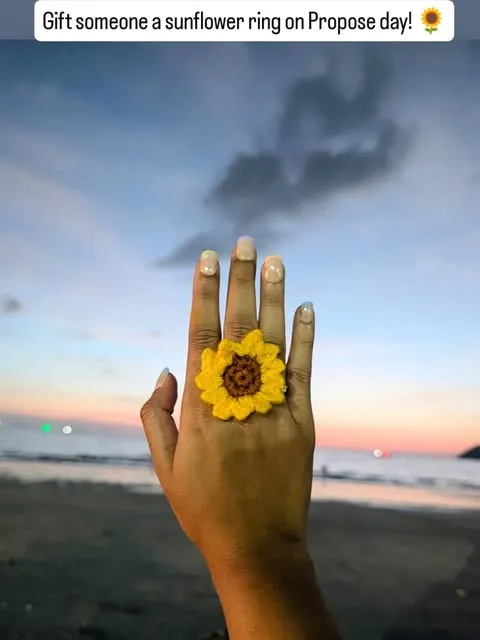 Crochet sunflower ring on a hand against a beach sunset